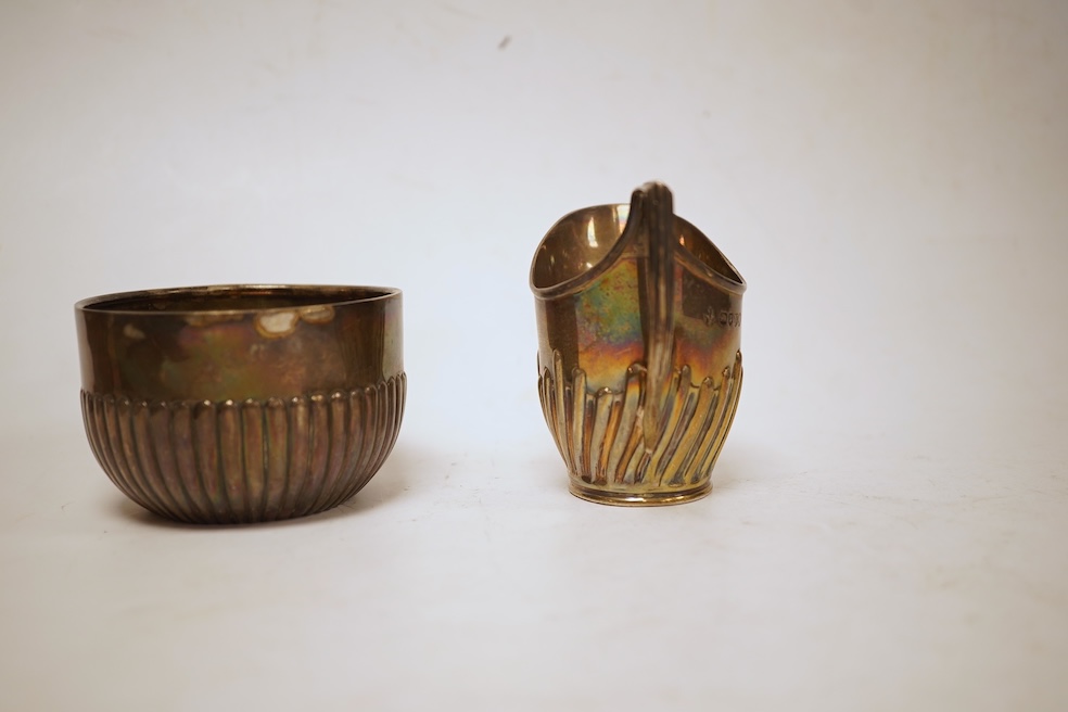 A late Victorian demi-fluted cream jug and sugar bowl, Charles Stuart Harris, London, 1888, together with cased silver christening egg cup, spoon and napkin ring and two other silver napkin rings.